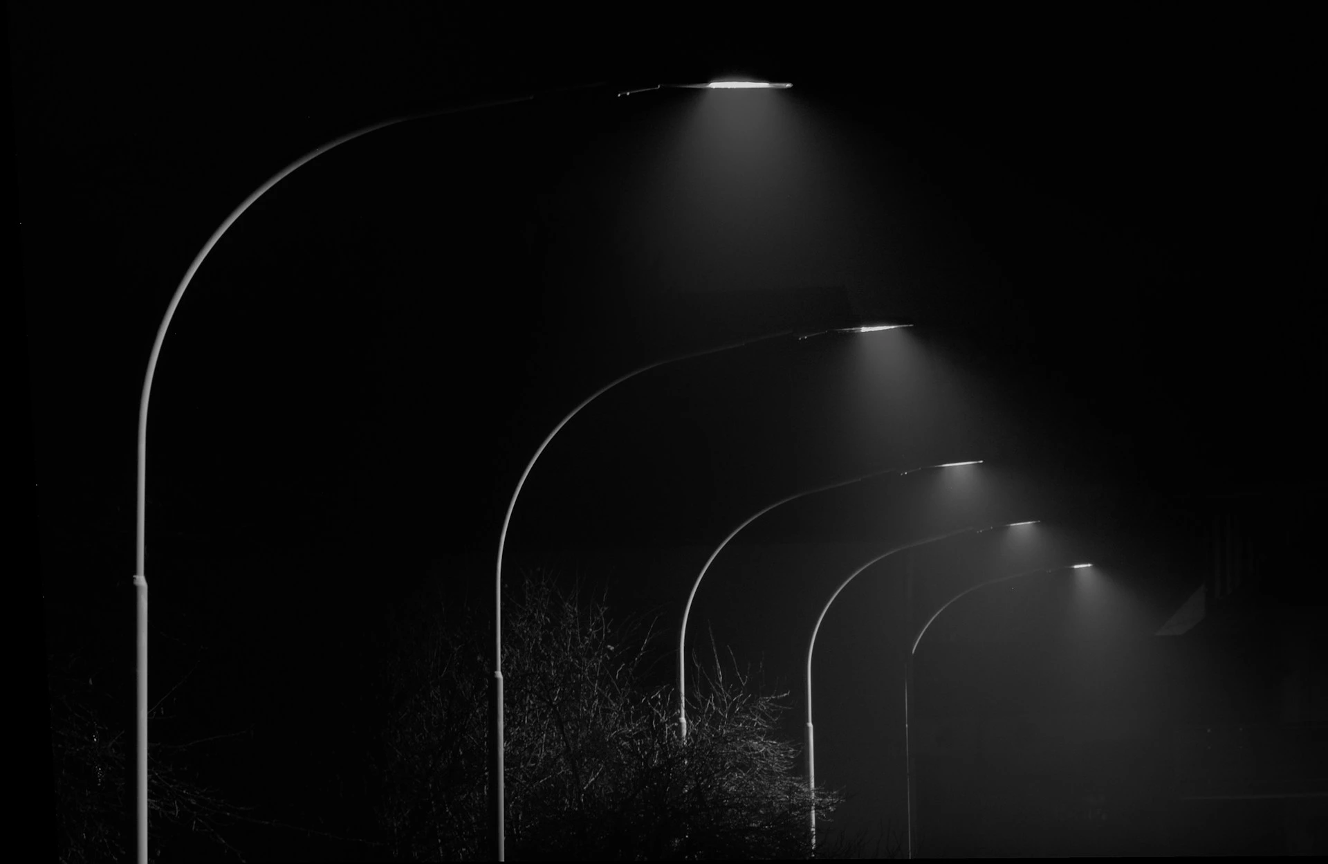 imagem mostra uma rua com postes de iluminação pública acesos.