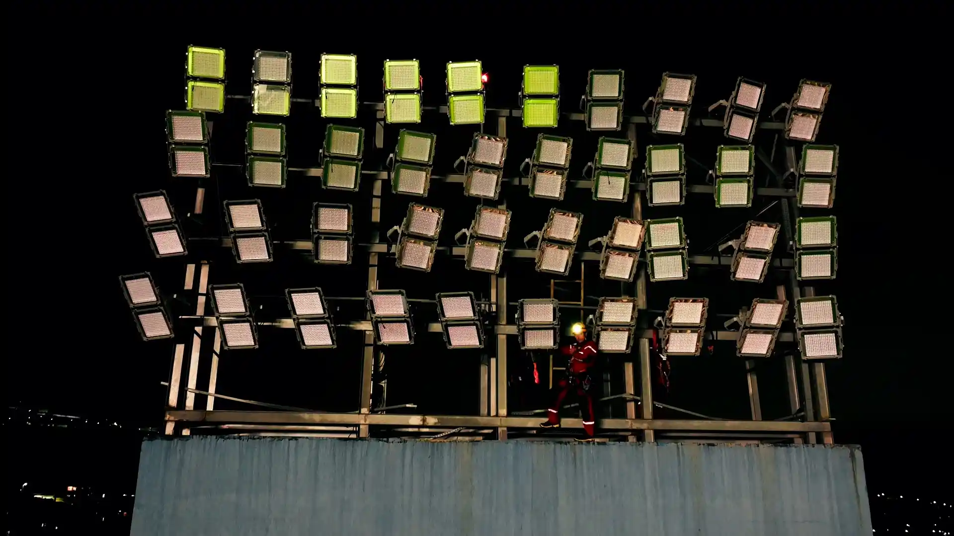 Imagem de uma pessoa fazendo manutenção em refletores esportivos