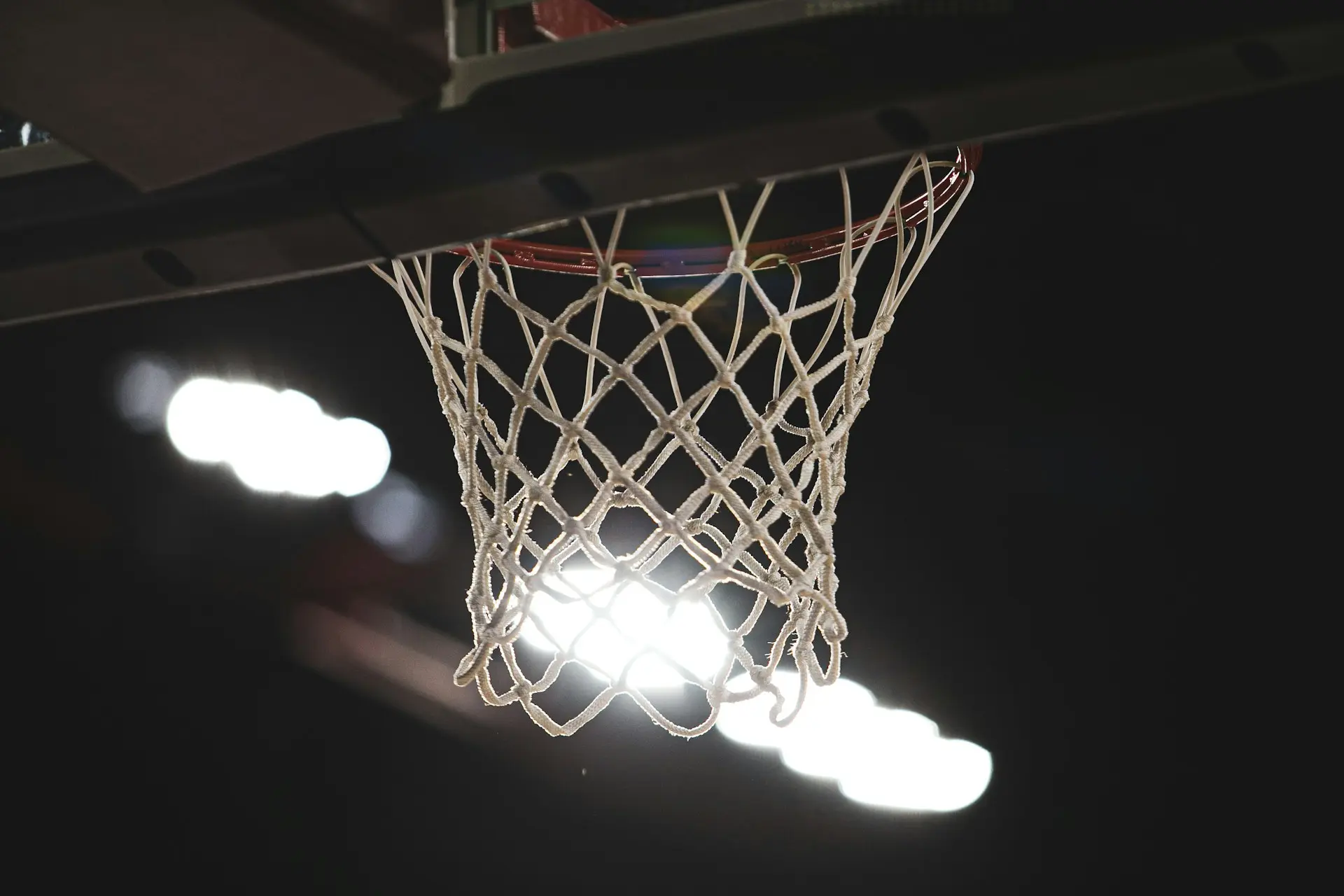 Imagem de uma cesta de basquete, com o fundo embaçado, mas bem iluminado.