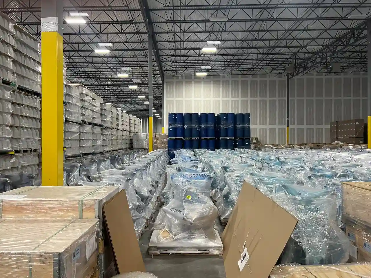 Imagem de um centro de distribuição com diversos pacotes empilhados e organizados para armazenamento e expedição.
