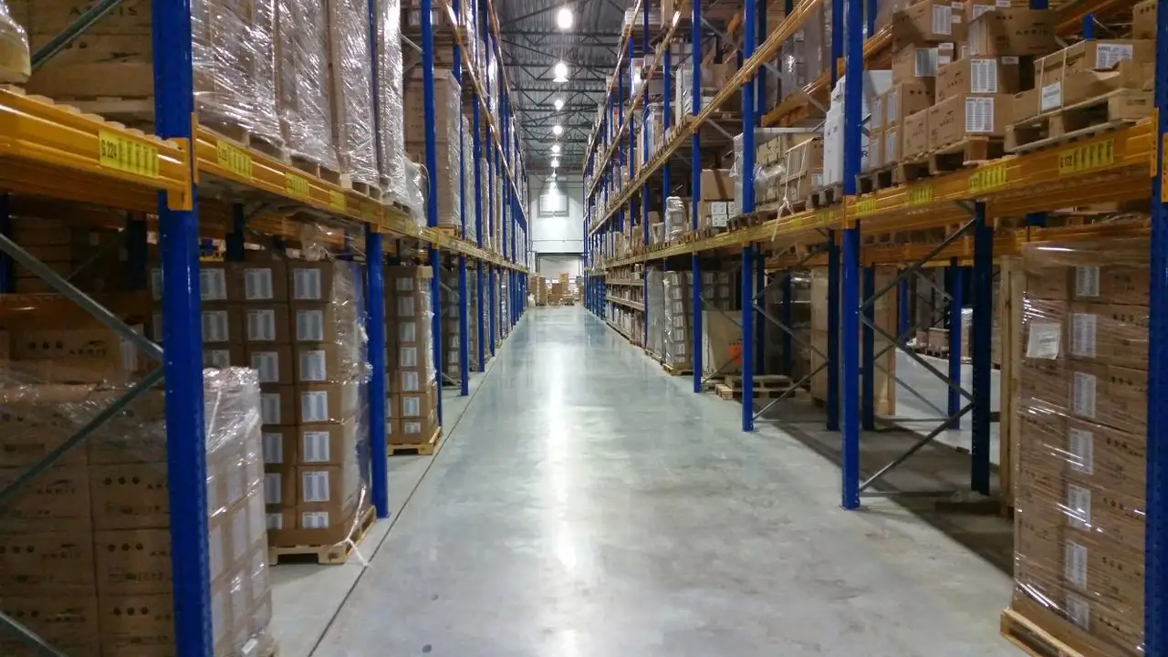 Imagem de um galpão com diversas mercadorias armazenadas em pallets e prateleiras.