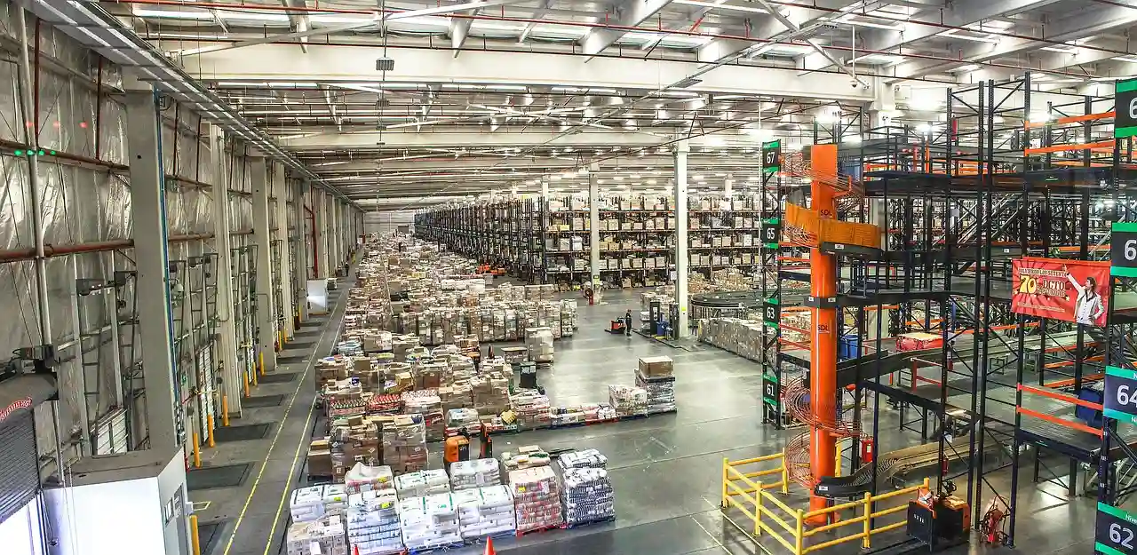 Imagem de um galpão com diversas mercadorias armazenadas em pallets e prateleiras.